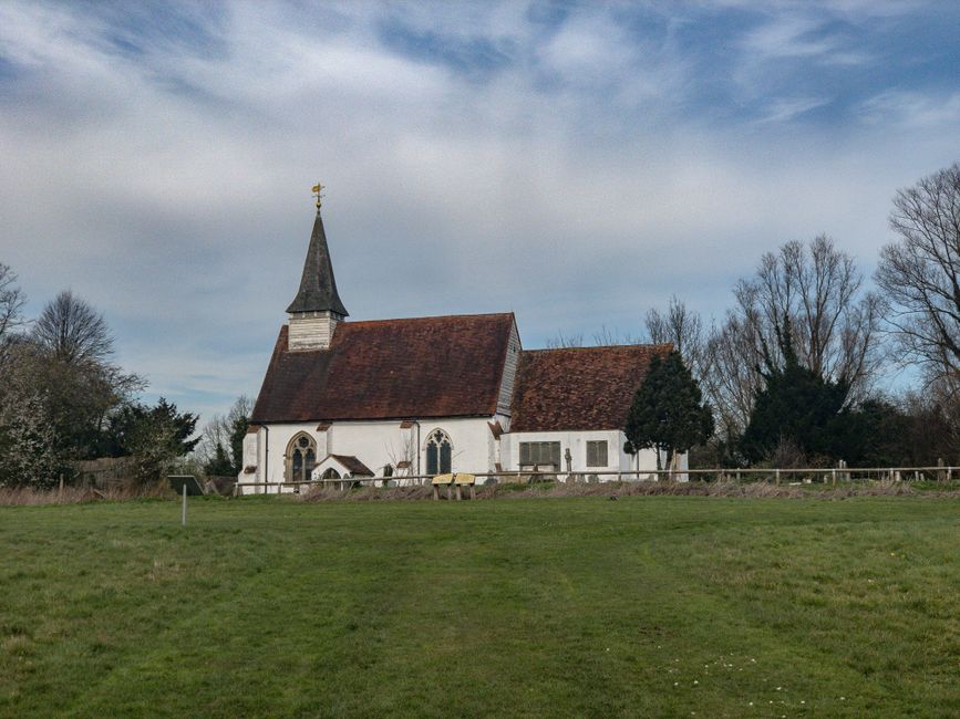 There is no image provided of flowers or floral arrangements; the image depicts a small white church with a steep red tiled roof, a pointed steeple topped with a cross, surrounded by trees and a grass